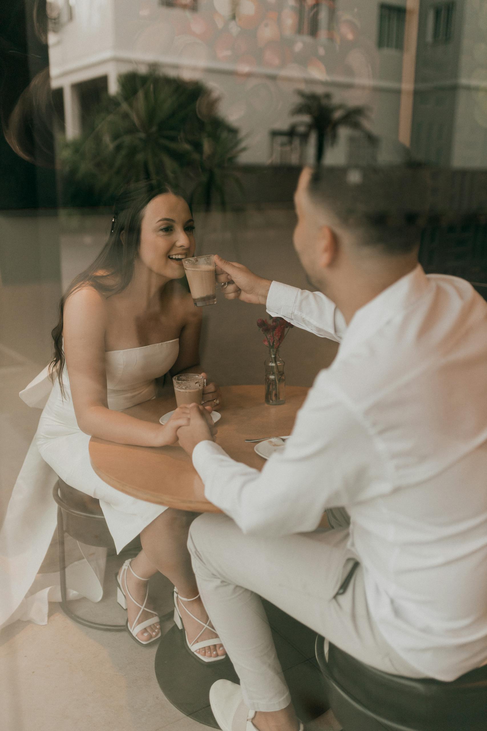 A newlywed couple enjoys coffee indoors, with an intimate and warm ambiance.